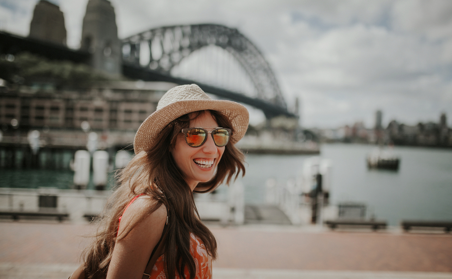 Happy smiling woman exploring Sydney, with Harbour Bridge in the background.