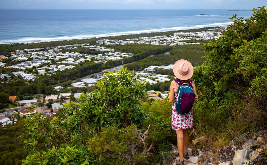hiker girl in a hat walking down the stairs from the top of mount coolum; hiking famous mount coolum near sunshine coast and glass house mountains, queensland, australia