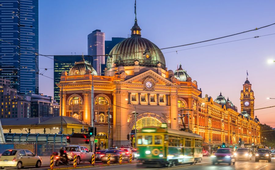 Melbourne Flinders Street Train Station with moving tram in Australia at sunset. 