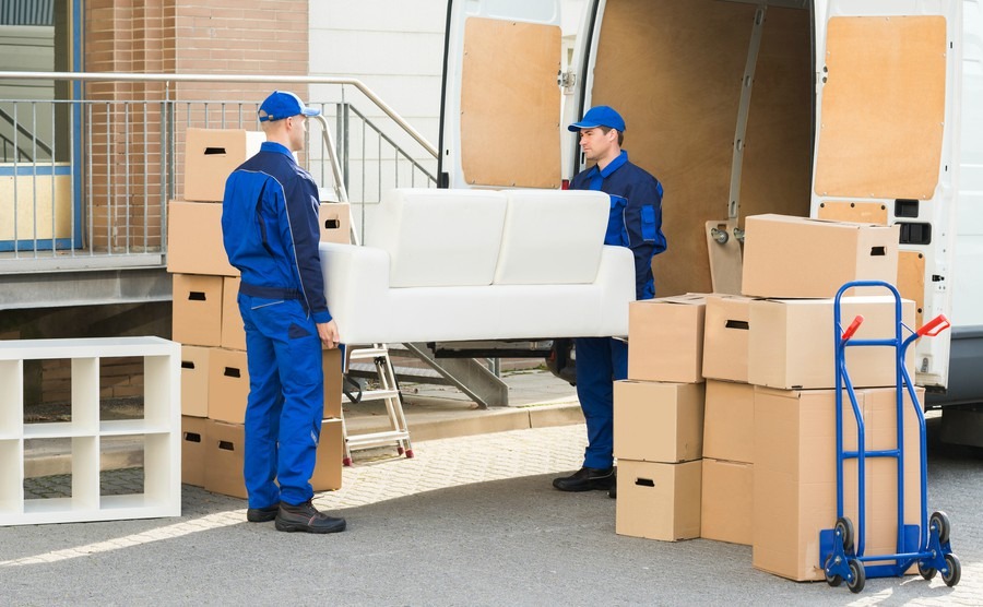 full-length-of-young-male-movers-carrying-sofa-outside-truck-on-street