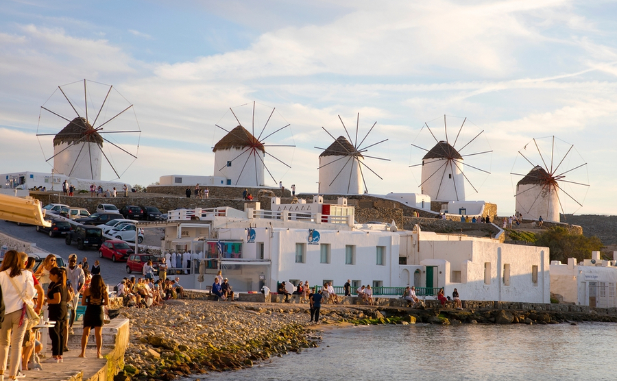 Mykonos, Greece - October 10, 2021: A beautful Light during the sunset on the waterfront and the famous Windmills of Mykonos, which were built in the 16th Century.