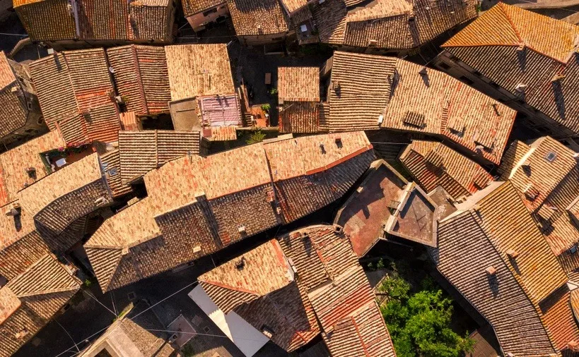 Perpendicular aerial view of red tile roofs of a small Italian mountain village. 