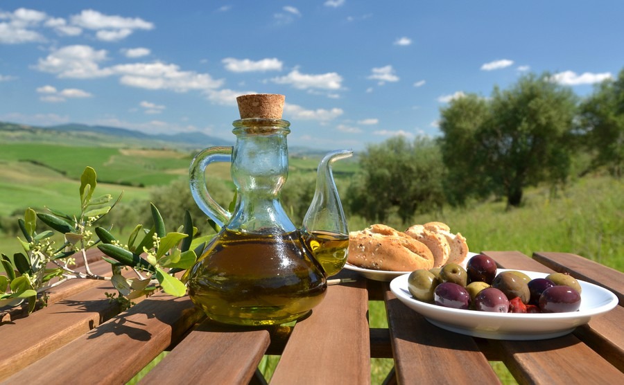 olive-oil-olives-and-bread-on-the-wooden-table-against-tuscan-landscape-italy