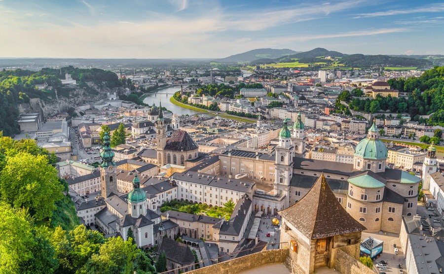 aerial-panoramic-view-of-the-historic-city-of-salzburg-with-salzach-river-in-beautiful-golden-evening-light-with-blue-sky-and-clouds-at-sunset-in-summer-salzburger-land-austria
