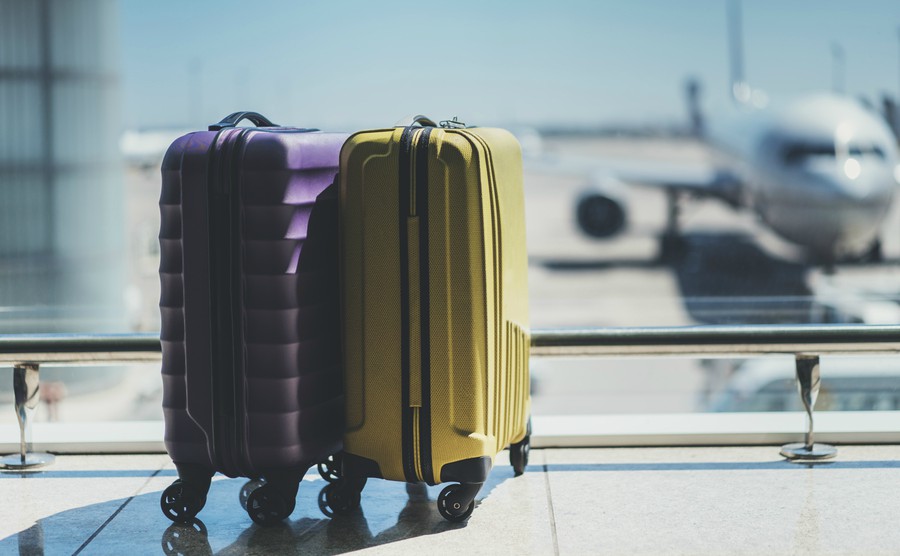 suitcases-in-airport-departure-lounge-airplane-in-background-summer-vacation-concept-traveler-suitcases-in-airport-terminal-waiting-area-empty-hall-interior-with-large-windows-focus-on-suitcases