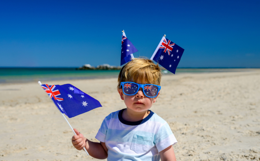 kid with Australian flags on the beach. 