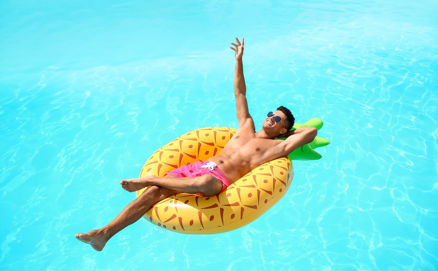 Handsome man with inflatable ring in swimming pool