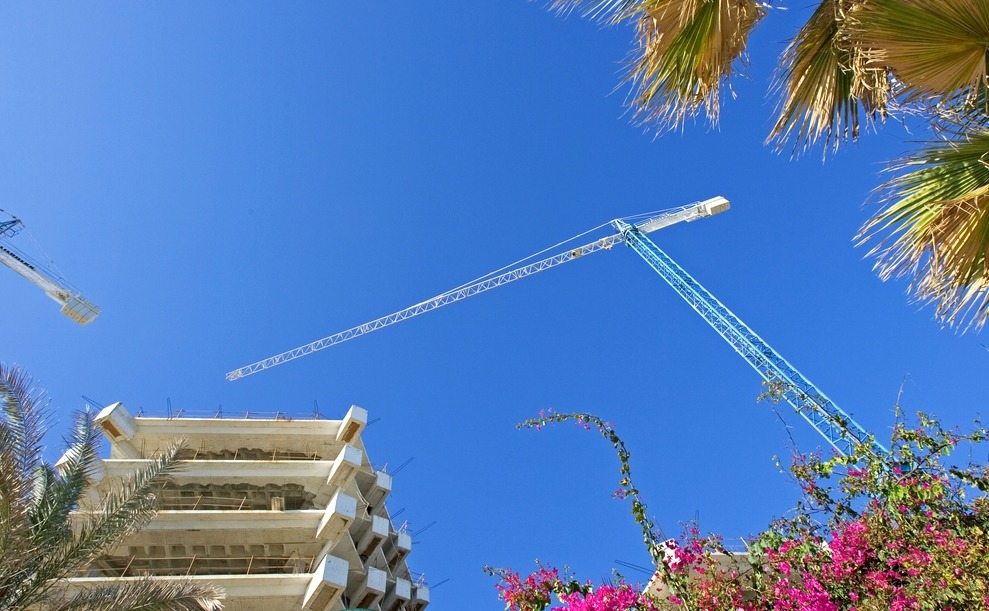 Cranes, buildings and flowers against a deep blue sky in Spain 