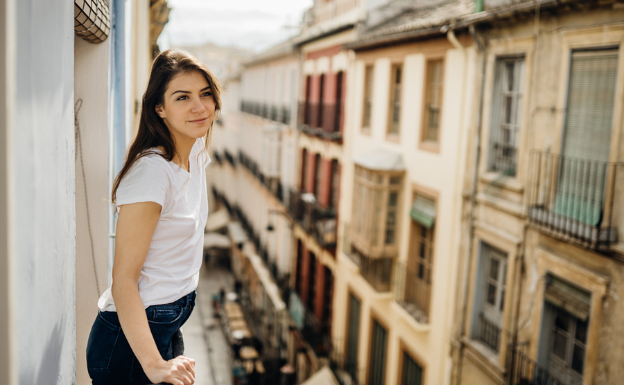 A woman on a balcony above a Spanish street. 