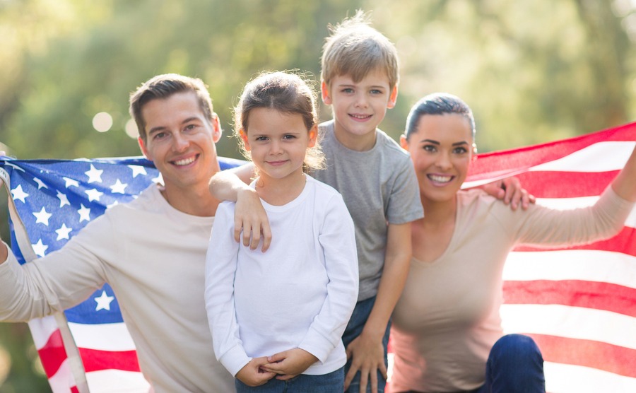 portrait of beautiful modern american family with USA flag outdoors